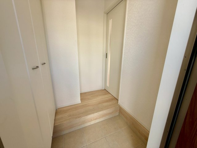 クレイドルガーデン那覇市識名 第３・１号棟の玄関|玄関の上がり框からリビングと階段へつづく廊下