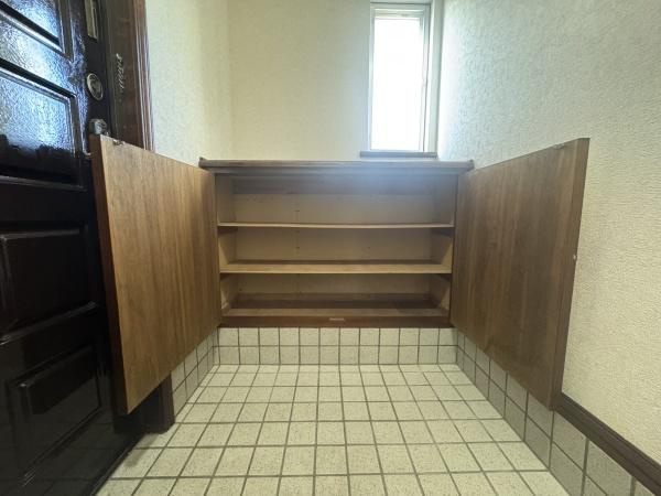 大字横尾　中古の玄関|タイル張りの玄関スペースに収納力のある下駄箱が設置されています。明るい窓から自然な光が差し込み清潔感のある空間です。扉付きの収納で整理がしやすい点が魅力です。使いやすい動線も確保されています。