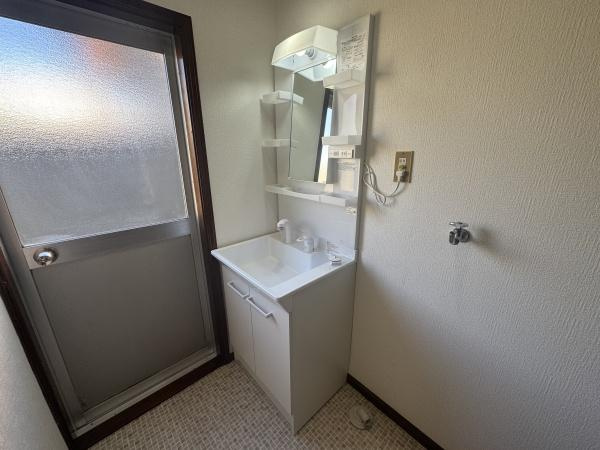 大字横尾　中古の独立洗面台|明るい洗面所で清潔感のある空間です。シンプルなデザインの洗面台が備わっています。ミラー横の収納スペースが活用しやすく整理整頓に便利です。窓付きで換気もしやすい仕様になっています。