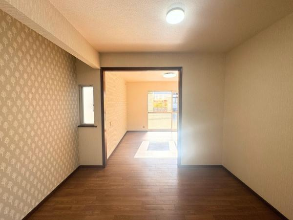 大字横尾　中古の居間・リビング|リビングは明るい光が差し込む空間です。落ち着いた雰囲気のフローリングが特徴です。壁紙のデザインもアクセントになっています。隣接した部屋との繋がりが感じられます。