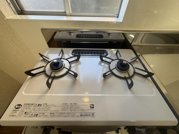 大字横尾　中古のキッチン|明るいキッチン空間に設置されたガスコンロはシンプルで使いやすいデザインです。2口タイプのため調理が効率的にできます。お手入れしやすい素材が採用されているのもポイントです。窓からの採光で換気も良好です。