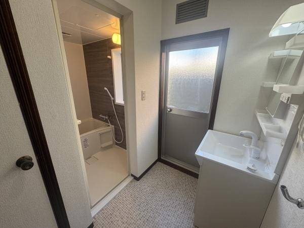 大字横尾　中古の独立洗面台|洗面台と浴室が隣接しており動線がスムーズです。シンプルなデザインの洗面台で空間がすっきりとしています。窓付きで換気がしやすい点もポイントです。壁面収納も備わっており使い勝手に配慮されています。