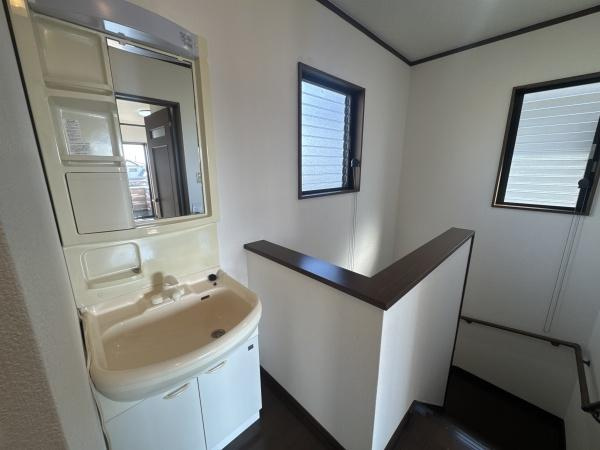 大字常行　中古の独立洗面台|明るい空間に設置された洗面台が清潔感を演出しています。収納スペースも備えられており使い勝手が良い仕様です。窓からの自然光がしっかりと差し込み快適に利用できます。階段近くの配置で移動も便利です。