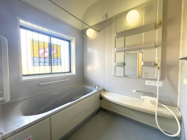 大字常行　中古の浴室|明るい窓があり日中も自然光が差し込むバスルームです。広めの浴槽でゆったりと入浴できます。壁面に鏡や収納棚があり実用性も兼ね備えています。シャワースペースも確保され使い勝手の良い設計です。