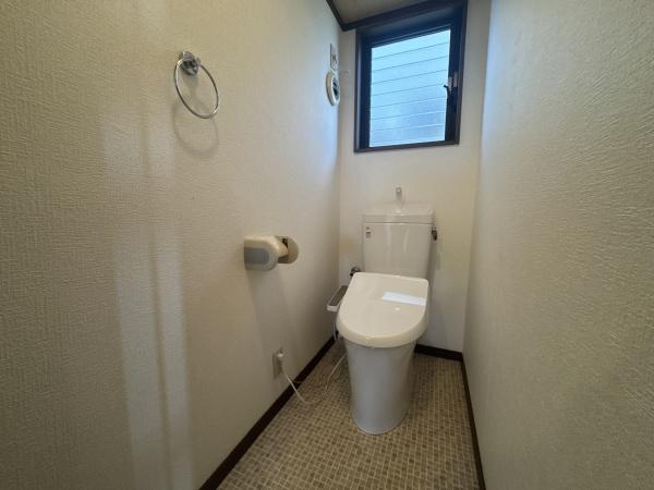 大字常行　中古のトイレ|シンプルなデザインで清潔感が感じられるトイレです。換気用の窓が設けられており明るさと通気性に優れています。壁面にはタオル掛けやペーパーホルダーも設置されています。