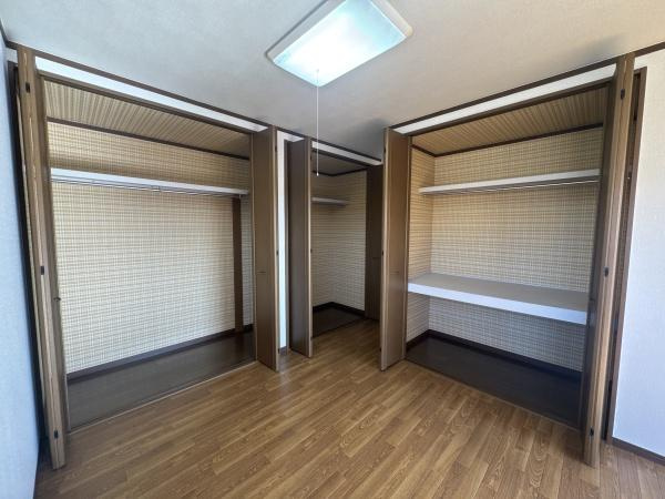大字常行　中古の収納|大容量のクローゼットが二つ並んでおり収納スペースがたっぷり確保されています。棚付きで整理しやすい設計です。木目調の床と扉が室内に落ち着いた雰囲気をもたらしています。