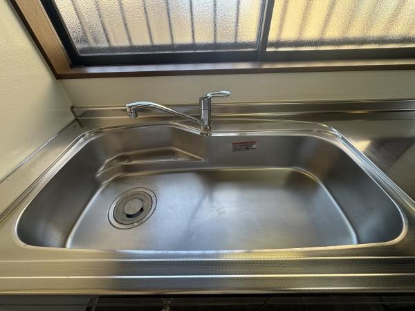 大字常行　中古のキッチン|ステンレス製のシンクが設置されていますのでお手入れがしやすい環境です。広めのシンクは使い勝手の良さが感じられます。大きな窓が近くにあるため明るい空間です。水まわりも清潔感が保たれています。