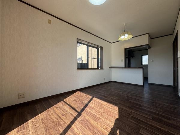 大字常行　中古の居間・リビング|大きな窓から光が差し込む明るいリビングです。木目調の床が空間に落ち着いた雰囲気を与えます。隣接するキッチンが見渡せる間取りとなっています。天井の照明がアクセントになっています。