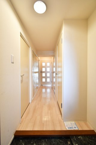 ソフィア上尾A棟の玄関|白基調で明るい廊下に収納を確保。散らかりがちな日用品を“見せずに”しまえて、帰宅後もすっきり。玄関→居室→水回りがつながり、毎日の動きが迷わずスムーズに整います。家全体が片付く感覚。