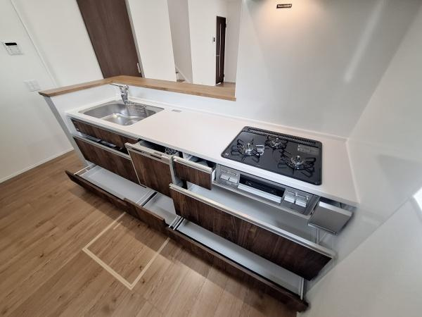 宗方台西1期1号棟のキッチン|キッチンには広々としたカウンターとシンクが設けられ作業スペースが確保されています。収納力のある引き出しが並び整理整頓しやすい設計です。ガスコンロとシンクの配置も効率的で日々の作業をサポートします。