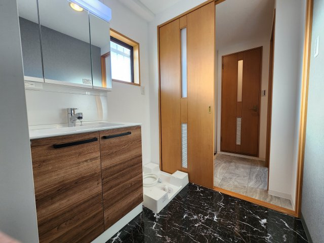 シャトー橿原の洗面所|窓付き洗面所の大きな二面鏡付き化粧洗面台、室内洗濯機置き場