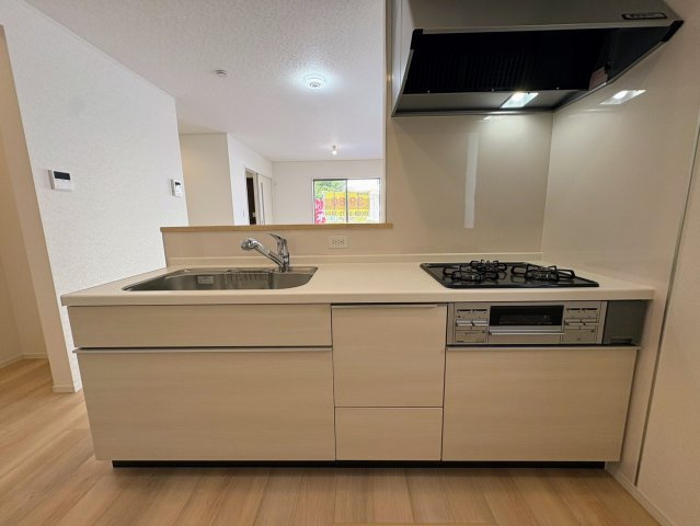 クレイドルガーデン那覇市識名 第３・２号棟のキッチン|レンジフード＆ガスコンロ３口＆浄水器付きキッチン／リビングの眺め