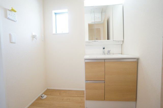 リナージュ美浜町奥田　1号棟の独立洗面台|シャワー付き洗面化粧台は、伸ばせる水栓で洗面台でのシャンプーや洗い物に便利な仕様。