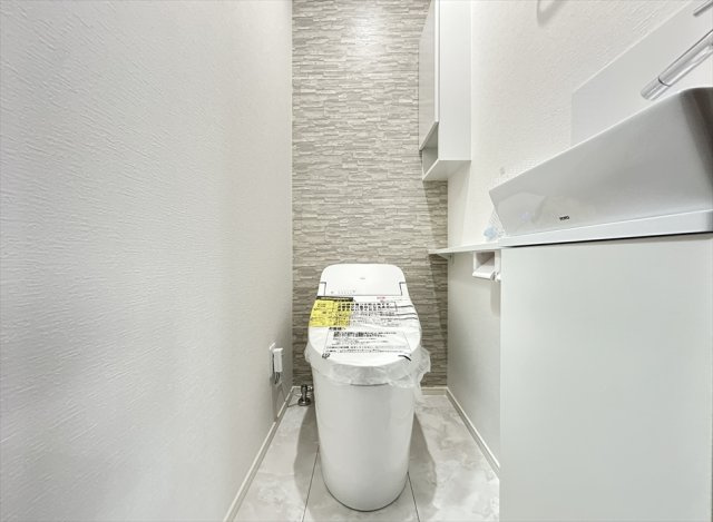 【トイレ】 | 新座市新座2丁目　新築一戸建住宅　全1棟　(志木本店) | 2階トイレ／衛生用品やトイレットペーパー、掃除グッズの保管に便利な壁面収納付でスッキリしたトイレ空間を維持できます。