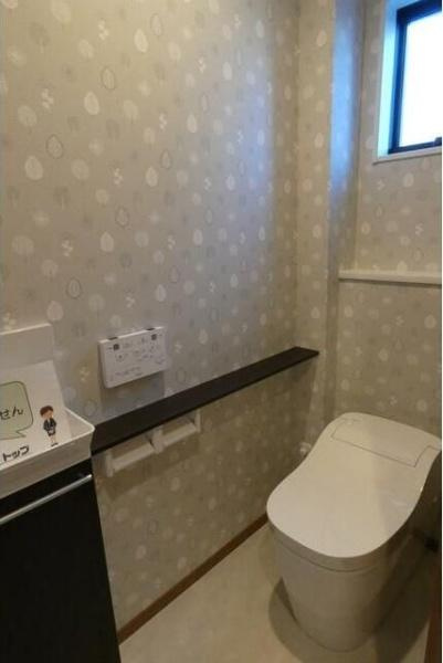 HT久原3号地のトイレ|窓が設置されており明るさと換気に配慮されたトイレです。壁紙のデザインが空間にやわらかな印象を与えています。使いやすい位置にペーパーホルダーや棚が設置されています。清潔感を感じる内装です。