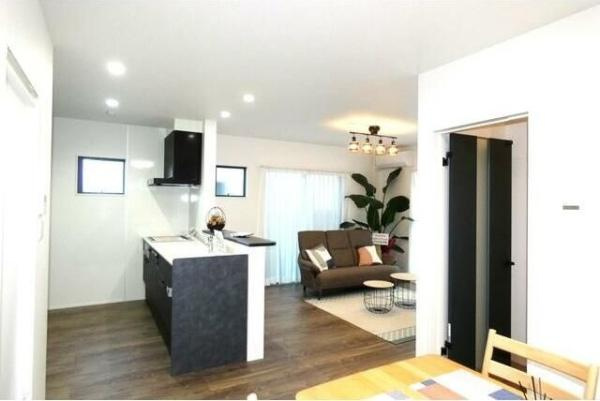 HT久原2号地の居間・リビング|リビングとキッチンが一体となった使いやすい空間です。ダウンライトやシーリングライトが明るさを演出しています。落ち着いた床の色合いがインテリアにも調和します。