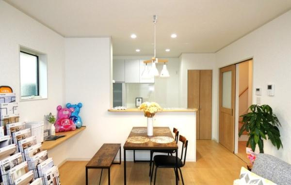 HT久原1号地の居間・リビング|リビングは明るく開放的な空間です。木目調のフローリングと白を基調としたインテリアが調和しています。天井にはダウンライトが設置されすっきりとした印象です。窓からやわらかな自然光が差し込みます。