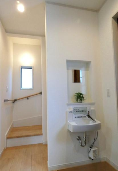 HT久原1号地の独立洗面台|シンプルなデザインの洗面台が設置されています。
壁のくぼみ部分にはグリーンが置かれておりすっきりとした印象です。
廊下からも使いやすい位置にあります。自然光が差し込む窓もあり明るい空間です。