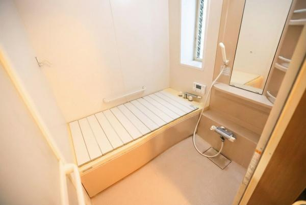 城東町　戸建ての浴室|使いやすさに配慮されたバスルームです。白を基調とした明るい空間が特徴です。大きな鏡と収納スペースも備わっています。