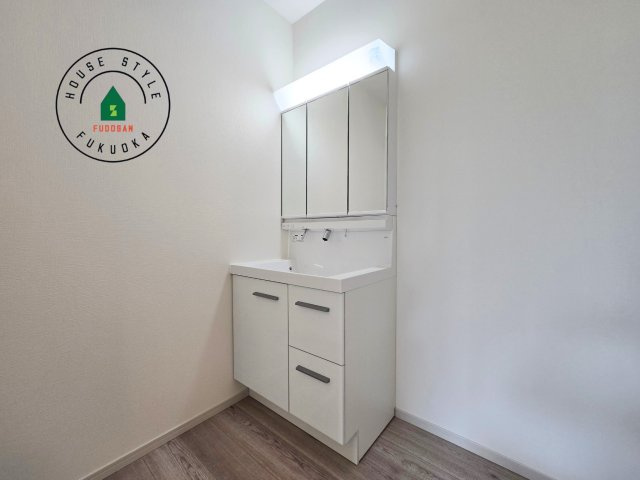 福岡市南区井尻4丁目第1-2棟（2号棟）の内観：施工例|毎日使うものだから清潔な空間を保ちたい水回り。洗面にはそんな願いを解消させてくれる収納アイデアが満載です。三面鏡の裏側にはキャビネットが現れ小物から背の高い物まで収納できます。