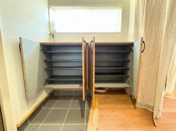 大字屋山　中古の玄関|玄関スペースには収納が充実しており靴や小物をすっきりと整理できます。窓から自然光が差し込み明るい印象の玄関です。床のタイルとフローリングが調和したデザインが特徴です。