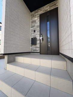 【玄関】 | 戸田　喜沢１　A号棟 | 重厚感ある玄関ドアが印象的。タイル貼りの階段と外壁が上質な雰囲気を演出します。