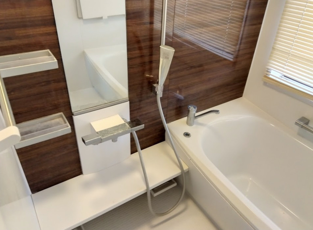 三島市谷田の中古マンションの浴室|木目調の落ち着いたアクセントパネルが、シンプルでモダンな空間に温かみを加えています。