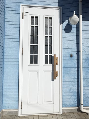 売中古戸建　清水町伏見の外観|爽やかなブルーの外壁に映える、白を基調とした玄関ドアが印象的です。縦長のガラス窓付きで、日中は自然光が入り、明るく開放感のある玄関スペースを演出します。