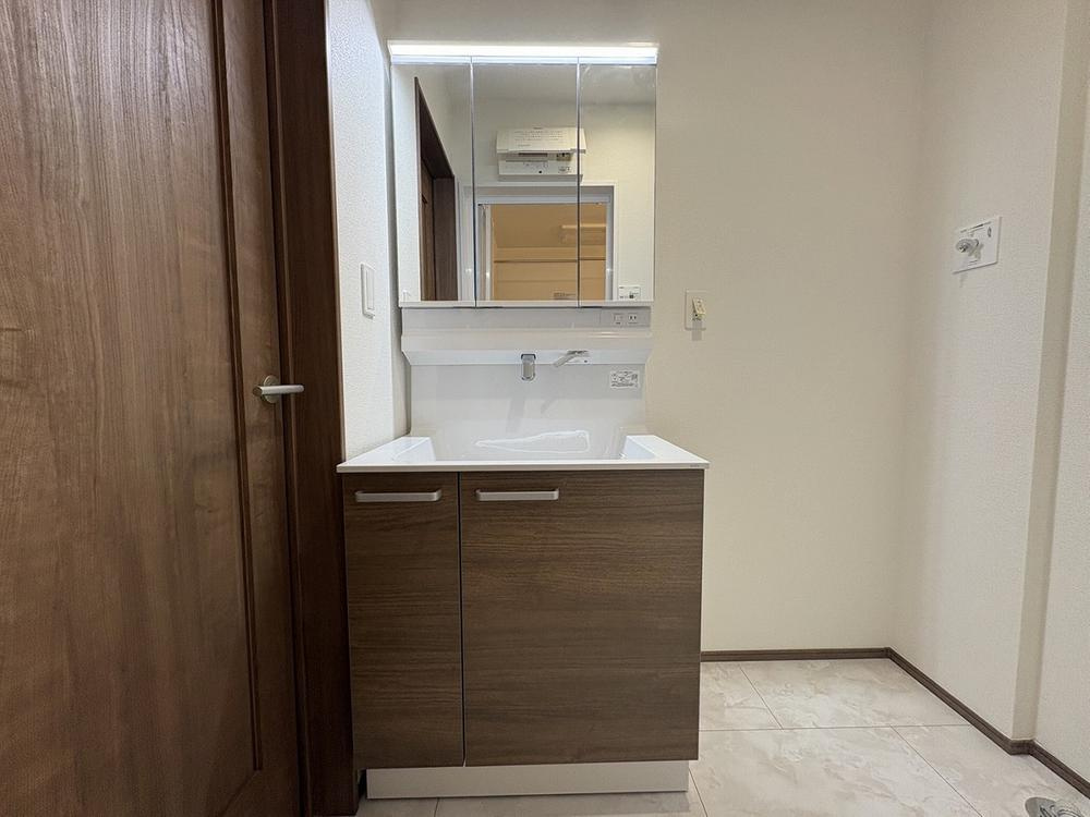 【Heartfull Town】小平栄町の洗面所|洗面台も収納豊富なのでかさ張るスキンケア品等も楽々収納できます。朝の身支度が時短にできそうですね。鏡も三面鏡になっておりますので背面の髪セット等も楽々行うことができますね。