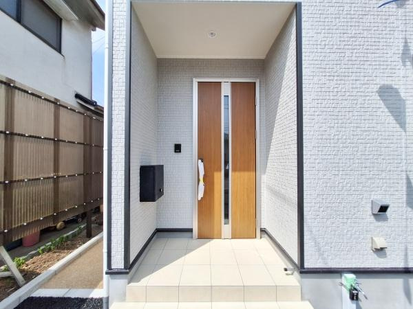 ふじが丘東第1-1号棟の玄関|玄関スペースは明るくシンプルなデザインが際立ちます。玄関ドアの木目調がアクセントになっています。手入れのしやすい床材が使われています。落ち着いた印象の外壁と調和した玄関です。