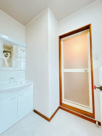 【脱衣所】 | 北見市中ノ島町３丁目１３番７号　中古売家 | 【リフォーム後】脱衣所の写真です。こちらは壁、天井クロスの貼替を行い、床のクッションフロアも張替を行いました。洗面化粧台も新設致しました。