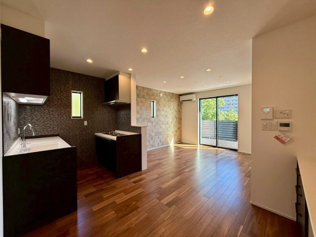 高知市一ツ橋町　新築一戸建ての居間・リビング|リビングとキッチンの色調を統一した落ち着いたデザイン。