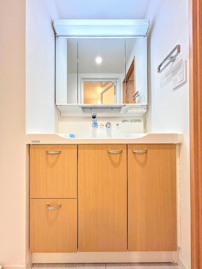 東戸塚緑の街四号棟の独立洗面台|◆三面鏡裏や、シンクしたにも多数収納を備えた、広々とした洗面化粧台。窓のある明るい洗面所で毎日の身支度も気持ち良くお使い頂けます。
