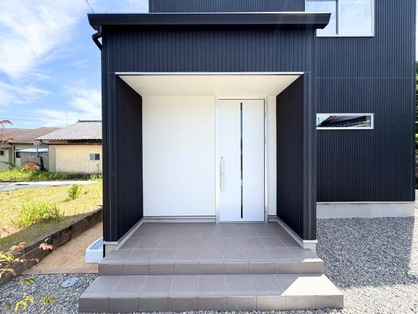 須賀一丁目　新築の玄関|シンプルで洗練された印象の玄関が建物全体に統一感を与えています。ホワイトとブラックの配色が際立ち現代的な外観です。段差のあるアプローチが玄関の存在感を際立たせています。屋根付きで雨の日も安心です。
