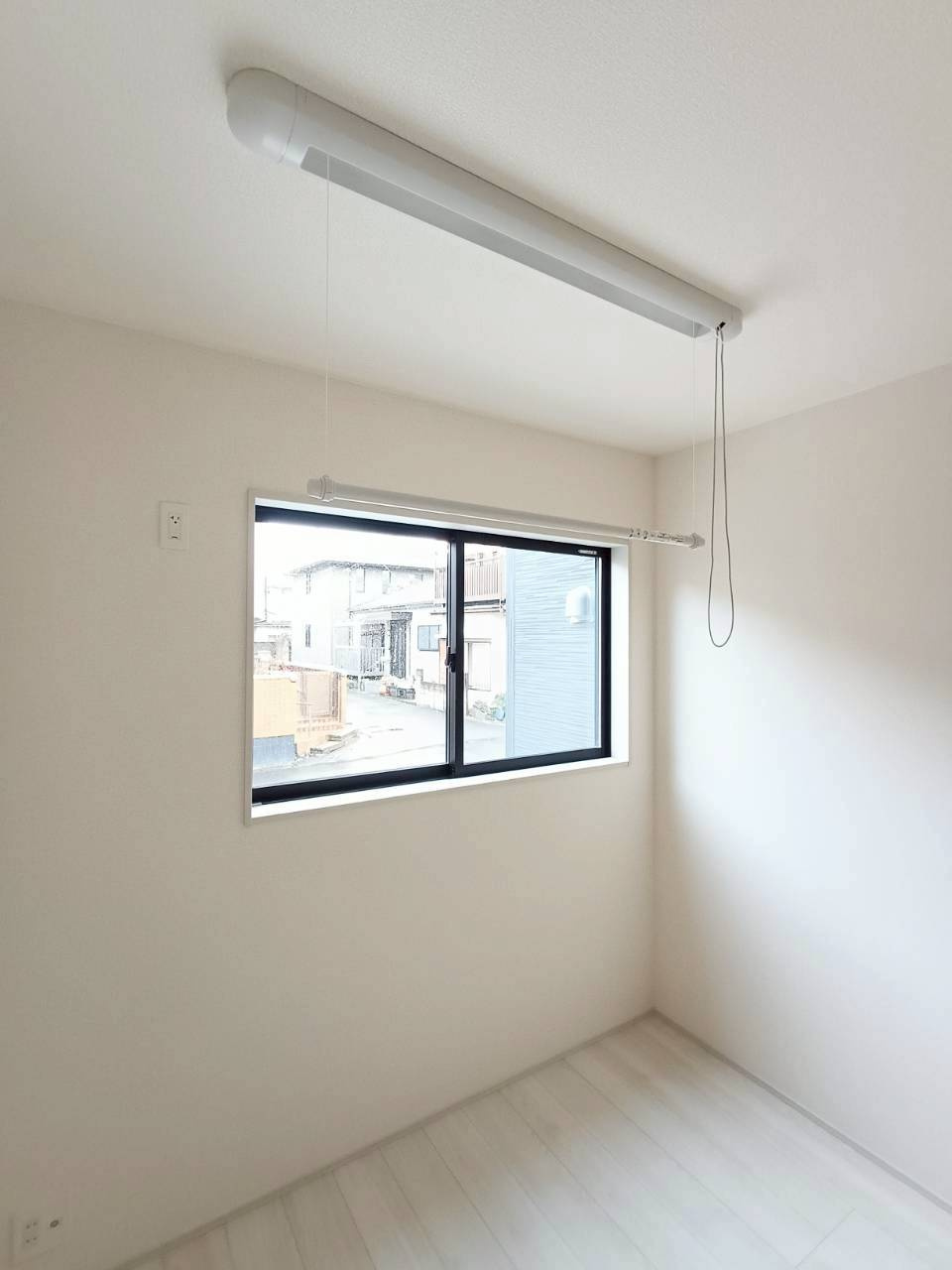 三郷市　東町　新築戸建　全1棟の設備|室内物干しを設置済みの便利な洋室。使わない時はすっきり収納できるため、お部屋の使い勝手も良好。共働きのご家庭や洗濯物が多いファミリーにも嬉しい、暮らしに役立つ設備です。