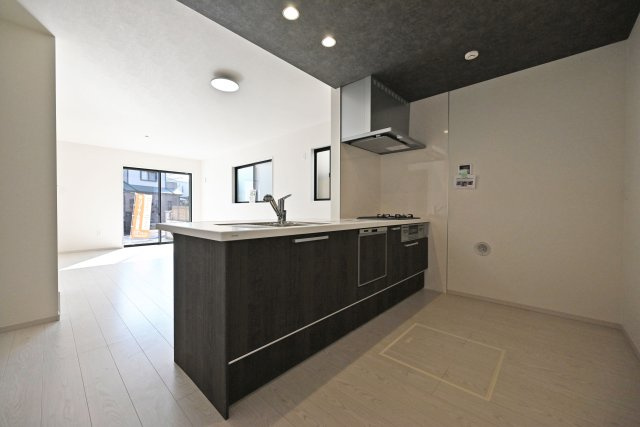 テラシエ寺本3丁目新築一戸建て│4LDK+駐車並列2台可(車種制限有)のキッチン|1階LDKをキッチン越しに撮影した現地内観写真です。 広くて使いやすいキッチンは折り下げ天井を採用しており、 オシャレな空間に仕上がりました。