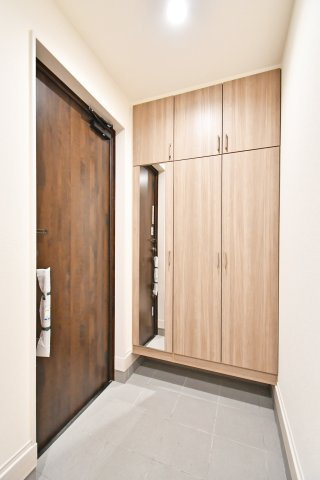 白岡市小久喜4期の玄関|天井まで届く大容量のシューズボックス付き。家族全員の靴をスッキリ収納でき、玄関を常に美しく保てます。お出かけ前の身だしなみチェックに便利な大型ミラー付。洗練された空間が、日々の帰宅を彩ります。