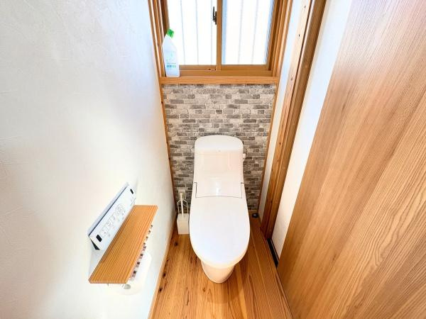 角子原二丁目　戸建てのトイレ|清潔感のあるトイレ空間です。木目調の床と壁が温かみを演出しています。窓があり自然光が差し込む明るい印象です。収納や小物置きにも配慮された設計です。