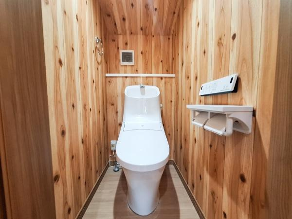 角子原二丁目　戸建てのトイレ|温かみのある木目調の壁が特徴的なトイレです。白を基調とした設備が清潔感を演出しています。収納やリモコンも使いやすい位置に配置されています。