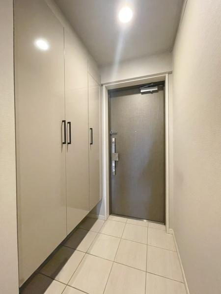 グリーンヒル大分駅前レジデンスの玄関|明るい照明が空間を引き立てます。収納スペースが充実しておりすっきりとした印象です。タイル床が上品な印象を与えます。ドアのデザインもシンプルで落ち着いた雰囲気です。