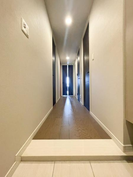 グリーンヒル大分駅前レジデンスの内装|玄関から続く廊下は直線的で空間をすっきりと見せています。照明が明るく奥までしっかりと照らされています。壁や床の素材がシンプルで落ち着いた印象を与えます。幅のある廊下で移動がしやすい設計です。