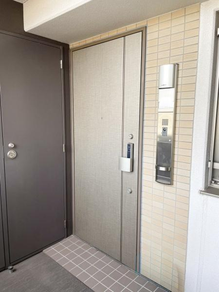 グリーンヒル大分駅前レジデンスの玄関|玄関ドアは落ち着いたカラーで外壁のタイルと調和しています。インターホンもスマートに配置されています。足元のタイルは清潔感があります。玄関周りがすっきりとした印象です。
