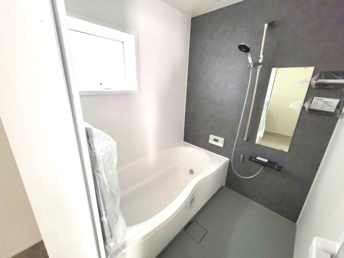 売新築戸建　沼津市東椎路の浴室|窓があるので明るい室内です。お子様と一緒に入っても窮屈さを感じない十分な広さになっています。グレーのタイルが可愛らしいです。