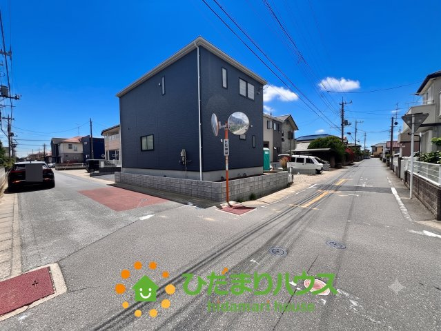 加須市南町第3　新築一戸建て　01　クレイドルガーデンの前面道路含む現地写真|鮮やかな青空を背景に、ネイビーと木目調のアクセントウォールが映えるおしゃれな外観ですね。