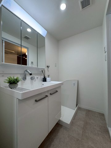 コスモ萱島の独立洗面台|明るい三面鏡を備えた洗面化粧台です。隣には新調済みの洗濯パンもございます。