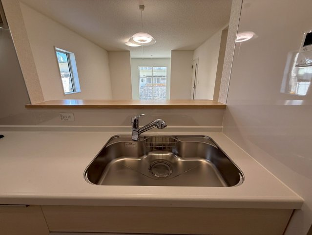 クレイドルガーデン糸満市座波 第２・２号棟のキッチン|浄水器付きキッチンの流し台／リビングの眺め