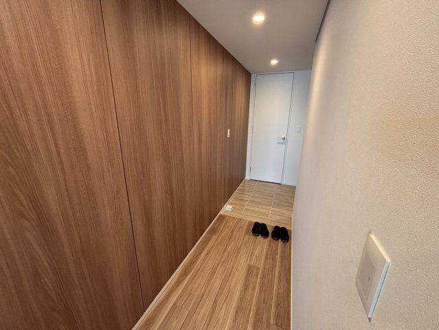 玄関横には大容量のシューズインクローゼットを配置。帰宅後すぐに荷物を置ける便利な動線です。明るいホワイトベースの内装に、温かみのある木目が映える、ゲストを心地よく迎える洗練された玄関空間です。