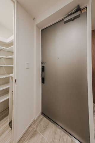 【洗練された住まいの顔】木目調の壁とタイルの質感が高級感を醸し出す玄関。大型の姿見は外出前のチェックに便利です。段差の少ないフラットな設計で、邸宅の風格と使い勝手の良さを両立しています。