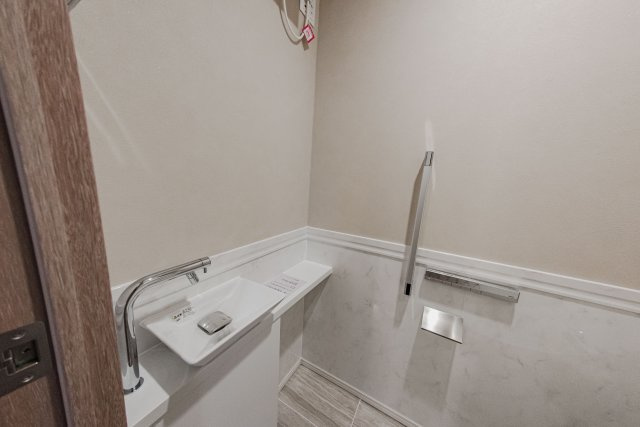 【清潔感溢れるトイレ】手洗いカウンター付きのタンクレストイレを採用し、スッキリとした空間に。上部には収納棚も完備しています。落ち着いた色調の内装が、プライベートな時間に安らぎを与えてくれます。