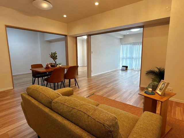 茨木南春日丘プライムタウンB棟の居間・リビング|【ＬＤＫ１６．１帖】洋室が隣接することで、生活動線がスムーズに。リビング中心の家族時間を保ちつつ、書斎や趣味部屋としても使える、多機能な住まい設計です。